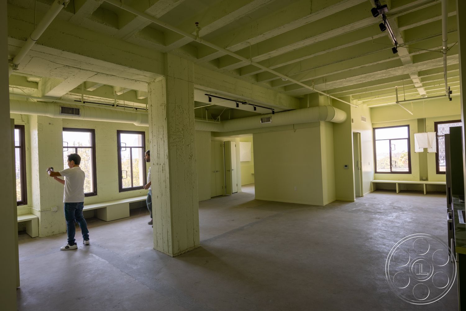 The Plaza - natural light, concrete flooring, interior space, exposed concrete walls, minimalist interior design, large windows with black frames, green painted walls, open ceiling with exposed beams, industrial-style space, benches along windows