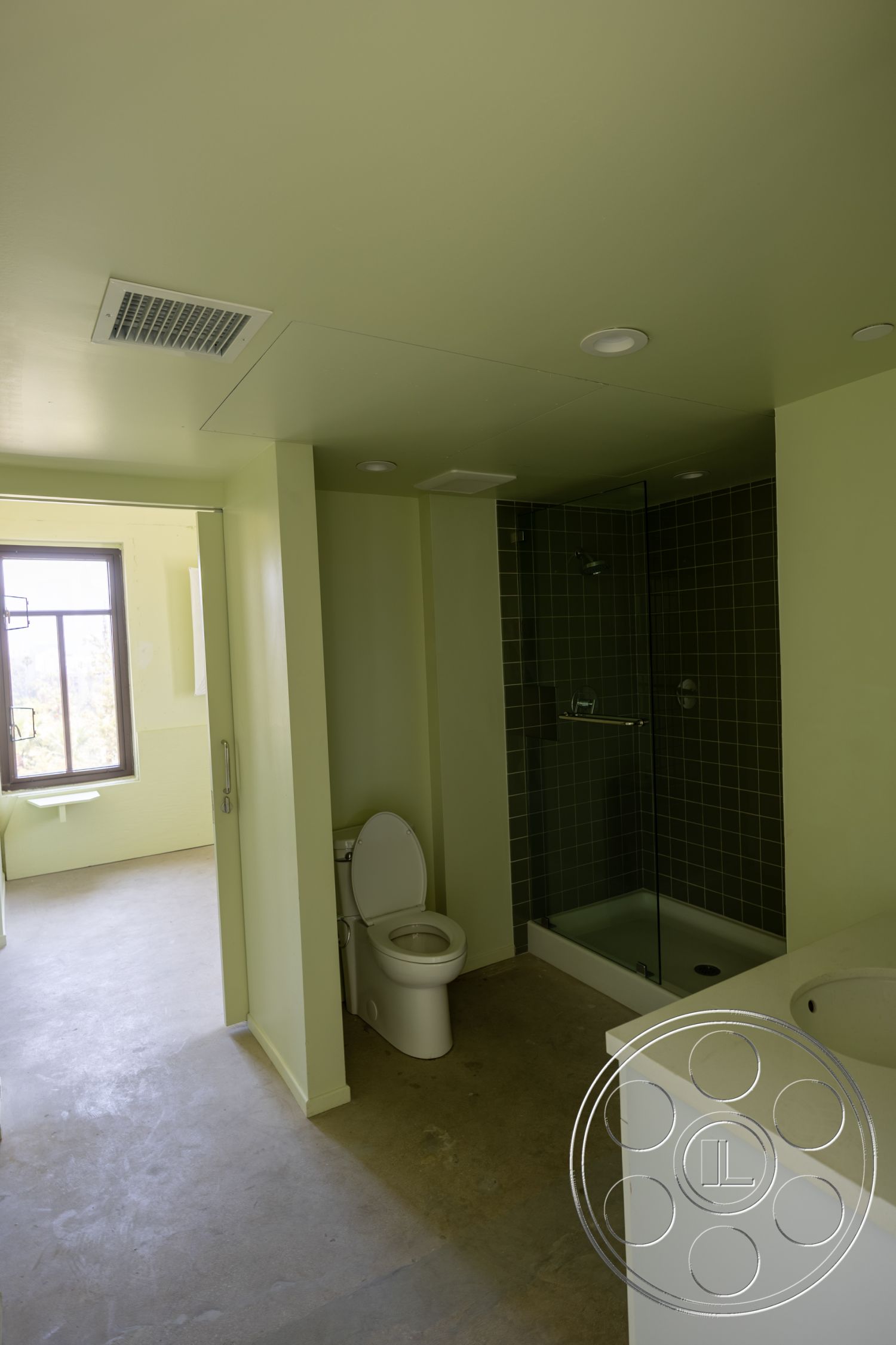 The Plaza - recessed lighting, minimalist design, glass shower enclosure, concrete flooring, floor-to-ceiling window, wall-mounted sink, modern toilet, green painted walls, ceramic tile bathroom wall