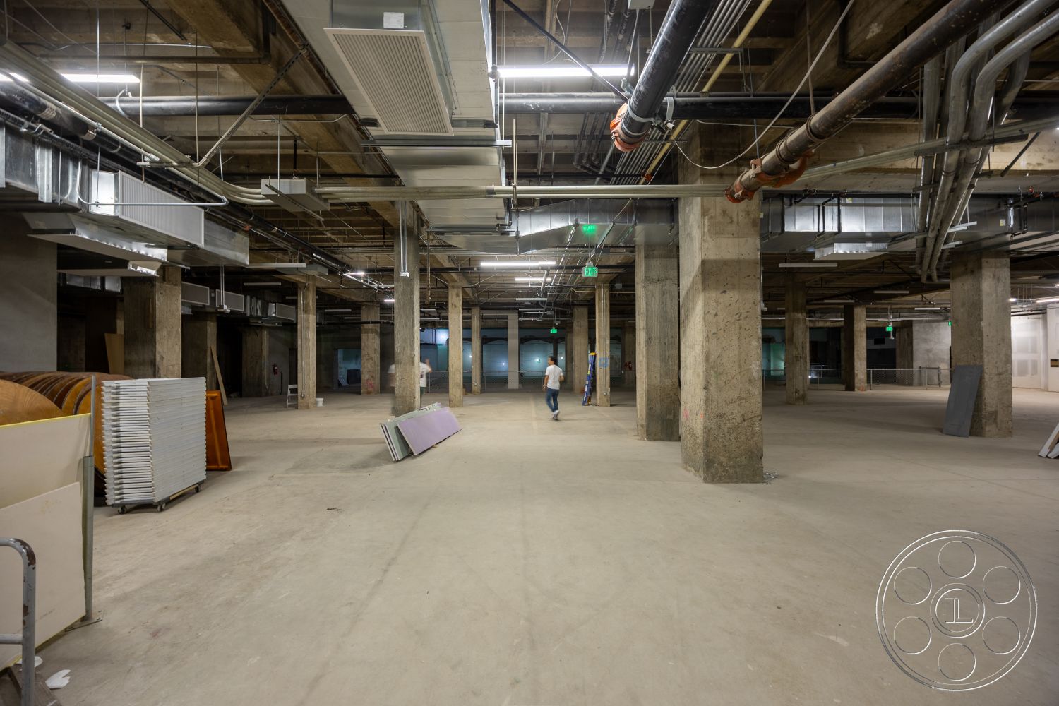 The Plaza - open floor plan, polished concrete flooring, interior space, exposed concrete walls, metal ductwork, overhead lighting fixtures, large open area, unfinished construction details, industrial ceiling with exposed beams, columns supporting structure