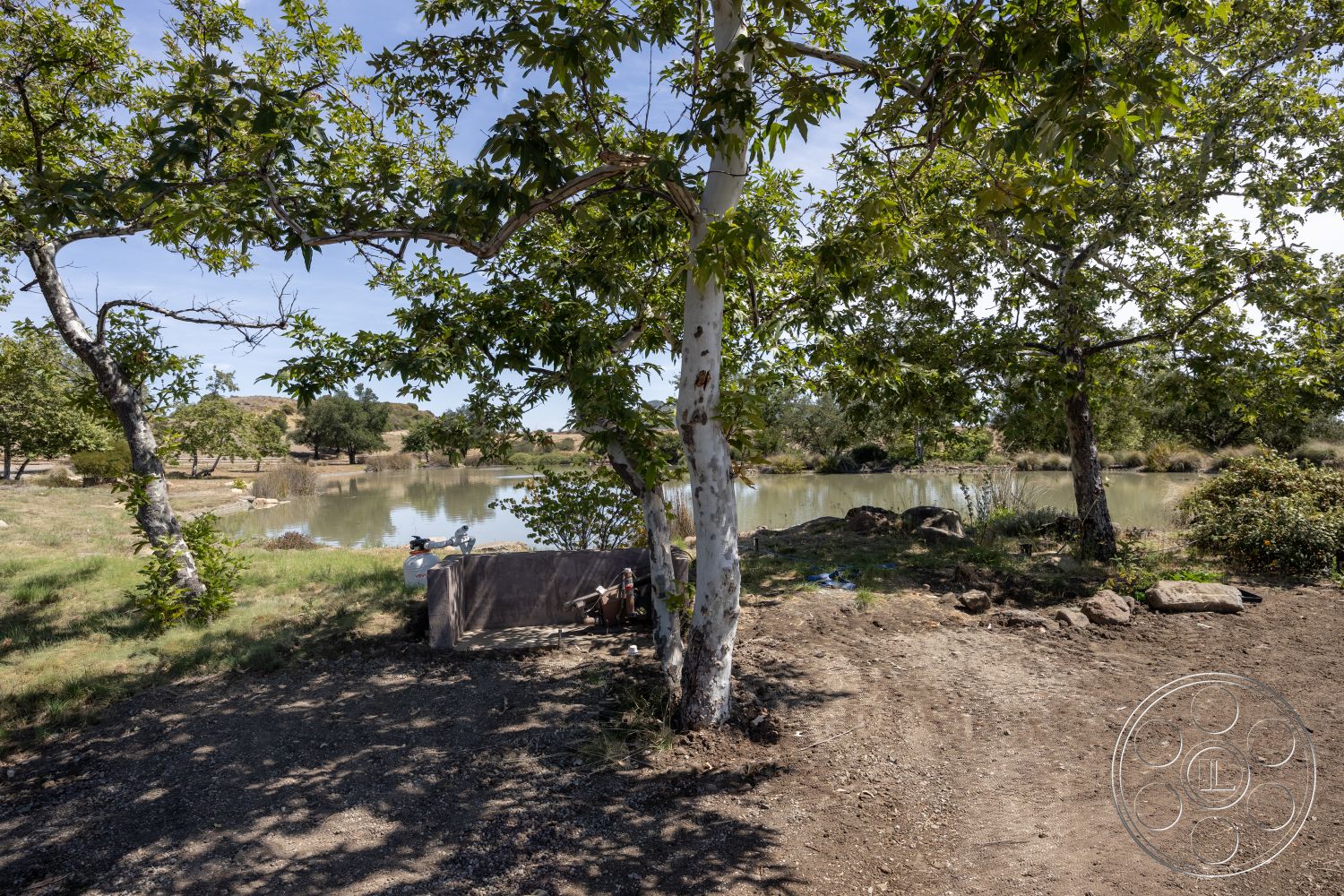 Eagle Feather - exterior, dirt path, mature trees, natural landscape, rock border, pond view, grassy field, scenic outdoor setting