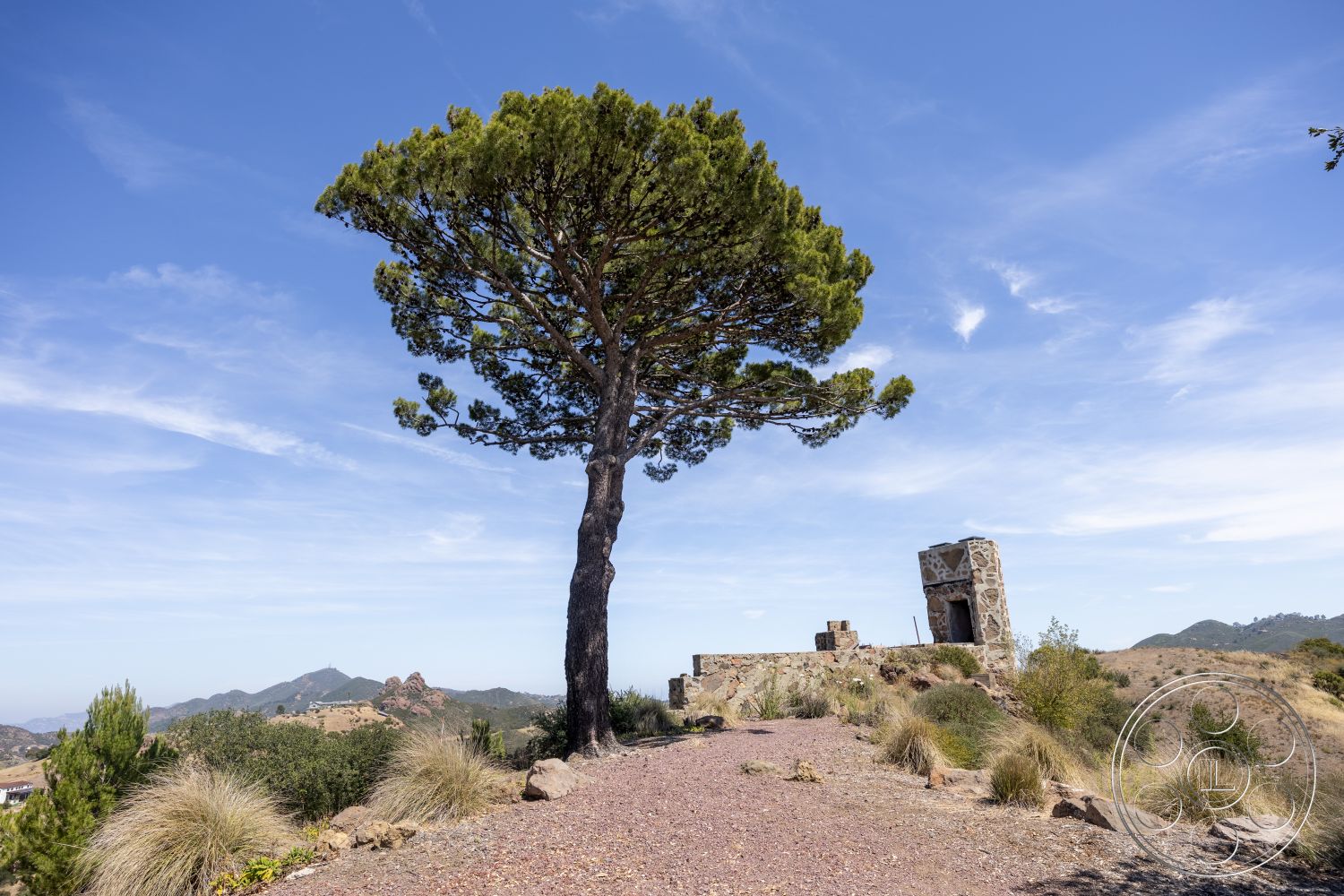 Eagle Feather - exterior, natural vegetation, clear blue sky, rocky terrain, desert setting, mountain landscape, distant mountain view, stone wall structure, large evergreen tree
