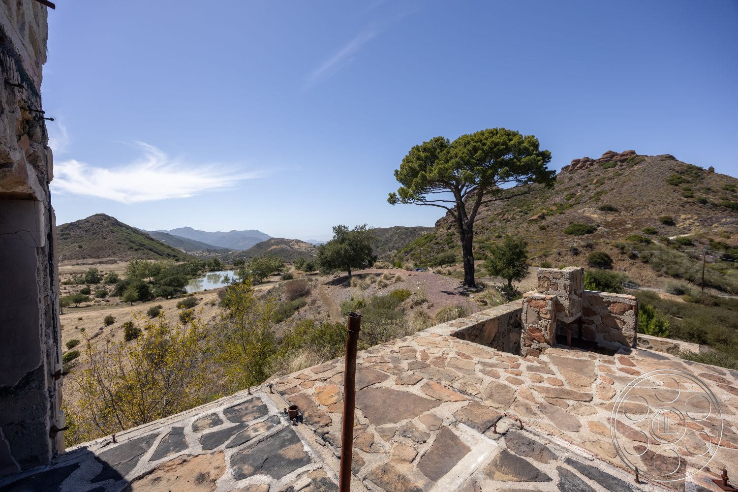 Eagle Feather - exterior, clear blue sky, mountain view setting, flagstone patio flooring, open outdoor area, stone wall construction, rustic stone fireplace, natural landscape environment, lone pine tree