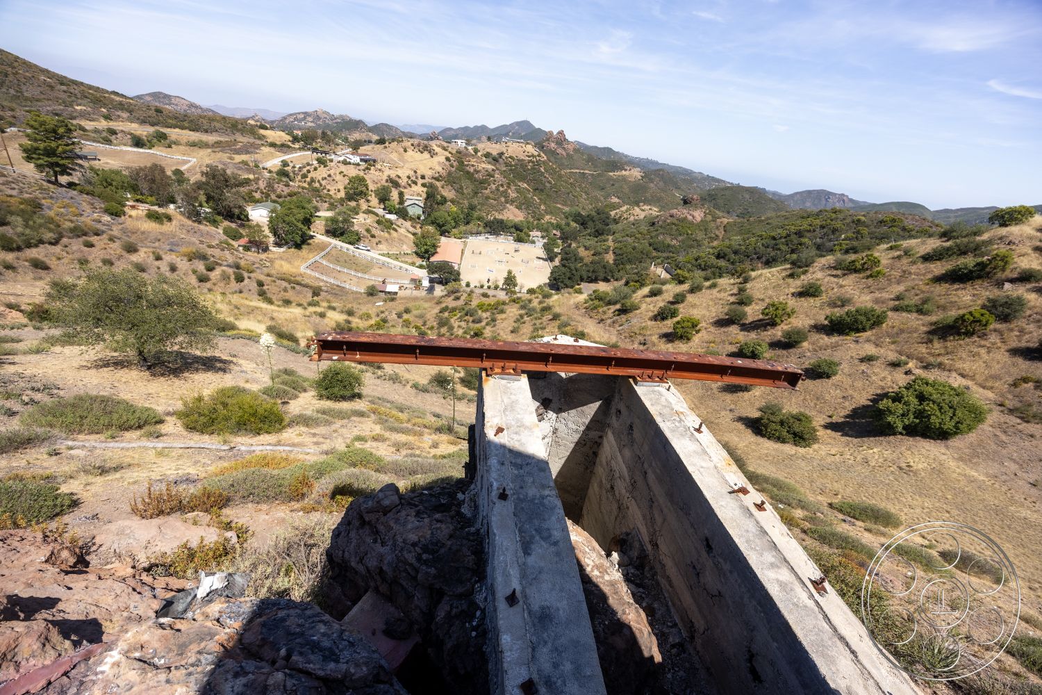 Eagle Feather - exposed concrete walls, concrete structure, mountainous landscape setting, natural terrain surroundings, steel beam, rusted steel elements, horizontal steel framing, arid hillside, industrial construction, vast scenic view