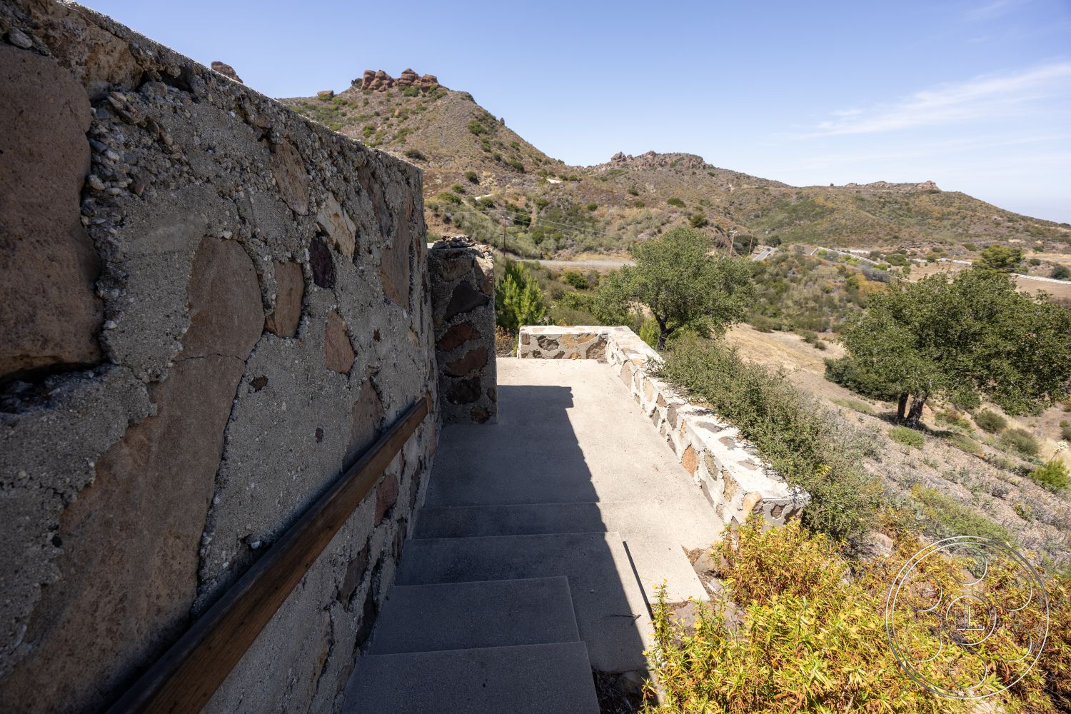 Eagle Feather - exterior, hillside location, stone retaining wall, landscaped garden area, exposed aggregate concrete steps, natural stone landscaping, wood handrail, rustic mountain setting