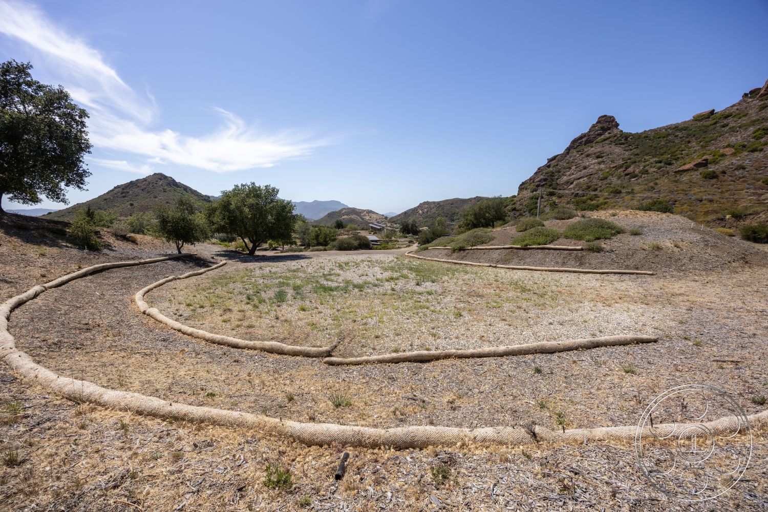 Eagle Feather - open field, natural hillside setting, outdoor landscape, drought-resistant foliage, curvilinear path formation, rocky mountain terrain, dry grassy area, irregularly shaped planting beds
