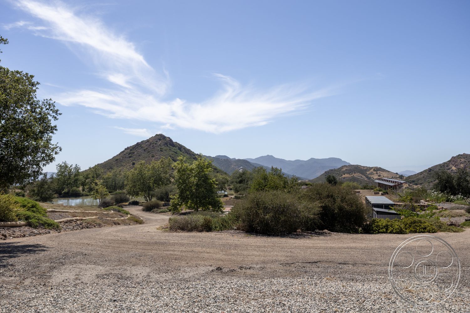 Eagle Feather - exterior, natural vegetation, rural setting, gravel driveway, mountain landscape, outdoor environment, sunny sky, pond feature, scenic hills, suburban property