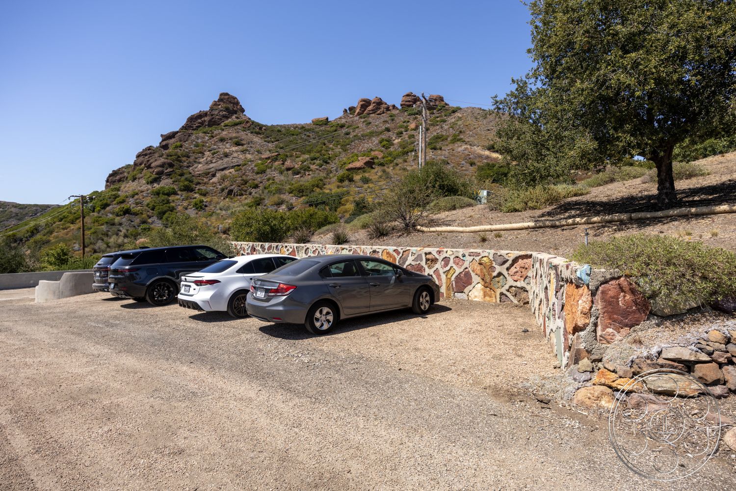 Eagle Feather - exterior, natural vegetation, blue sky, stone retaining wall, mountainous landscape setting, gravel parking area, irregular stone wall construction