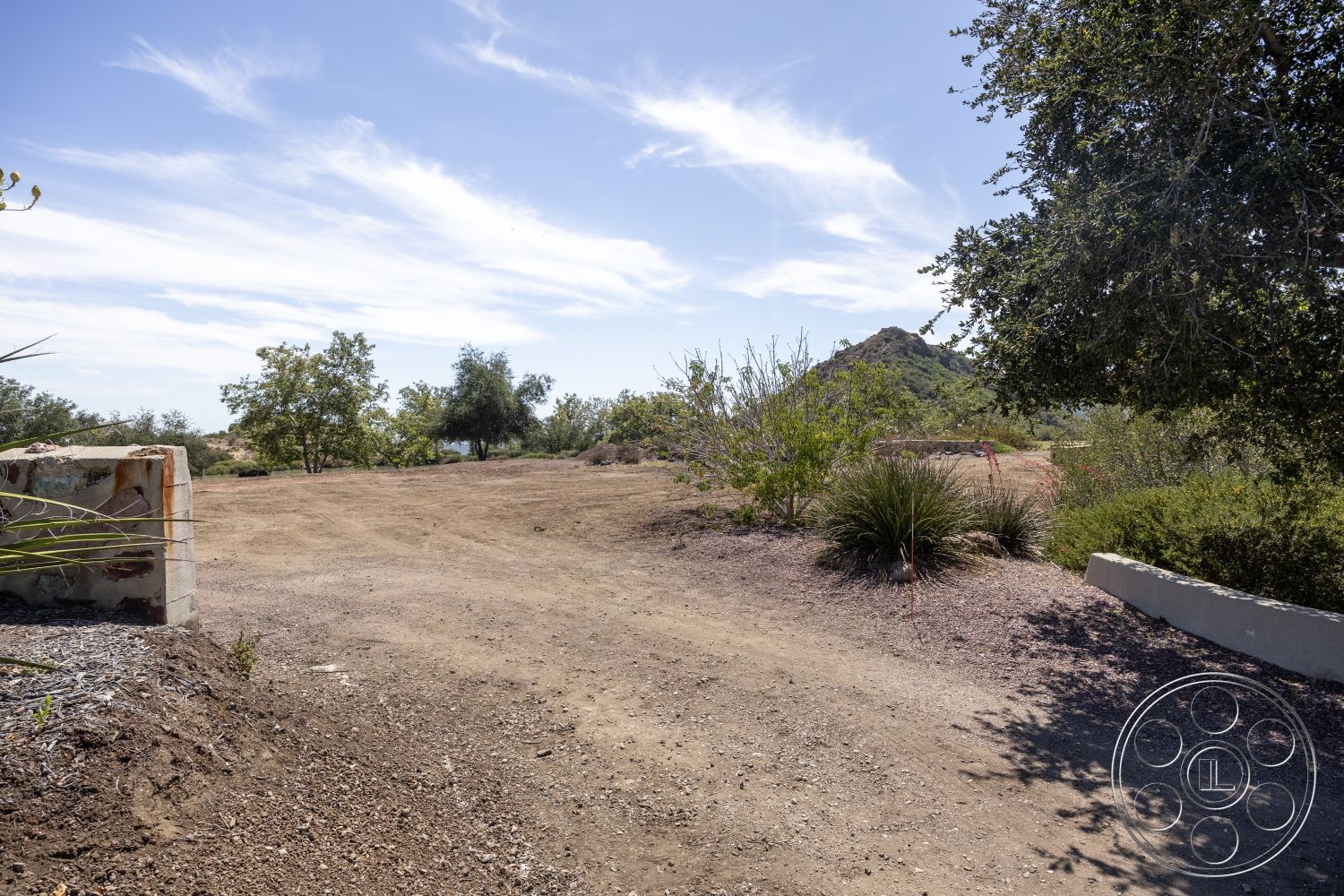 Eagle Feather - mountain view, dirt driveway, scattered shrubs, sunny exterior, natural landscape setting, low-lying vegetation, cleared land area, soft earth, exposed soil, rustic natural environment
