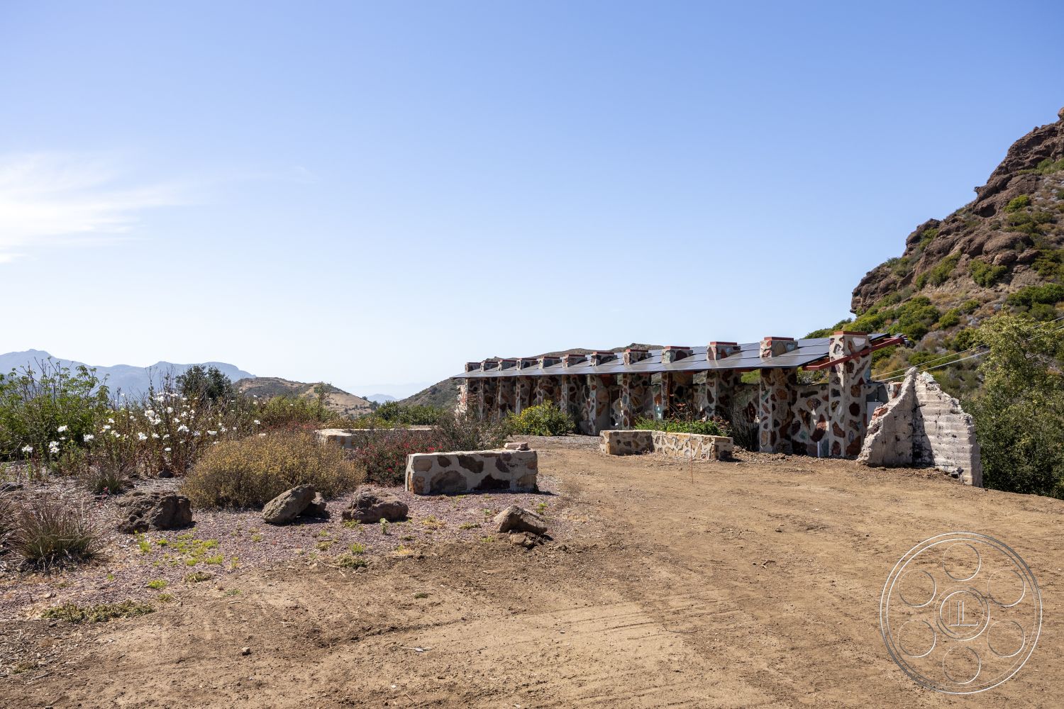 Eagle Feather - exterior, mountain backdrop, urban view, stone walls, dirt pathway, landscaped garden area, rustic architectural style, natural rock formations, wooden beam roof structure
