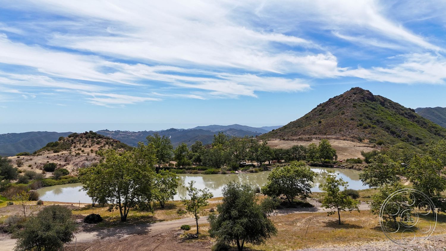 Eagle Feather - natural landscape, mountain backdrop, suburban backyard, hillside location, open sky, rural environment, cloudy blue sky, pond water feature, tree-filled setting