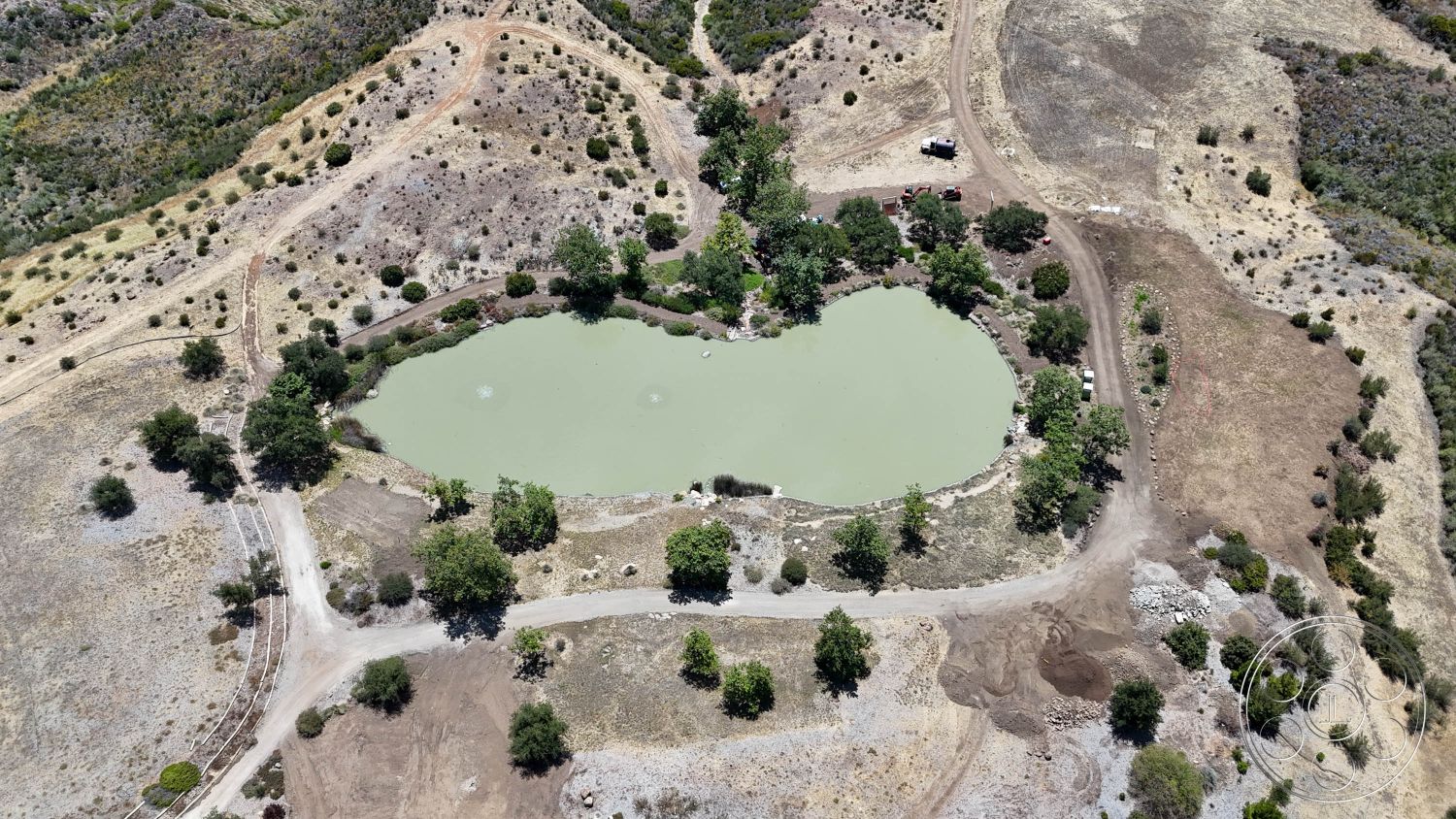 Eagle Feather - exterior, dry grass, shrubbery, scattered trees, grazing land, natural pond, earth-toned landscape, heart-shaped pond, dirt access roads, rugged terrain, rocky outcroppings