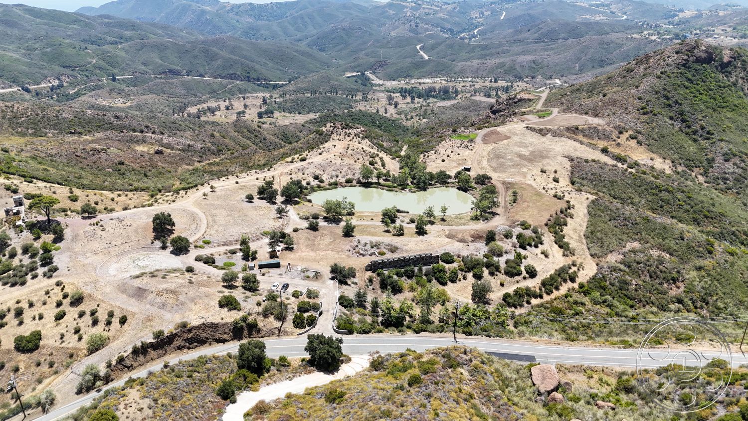 Eagle Feather - exterior, clear blue sky, open field, mountain landscape, scattered trees, curved road, natural vegetation setting, pond area, undulating topography, sunlit hillside
