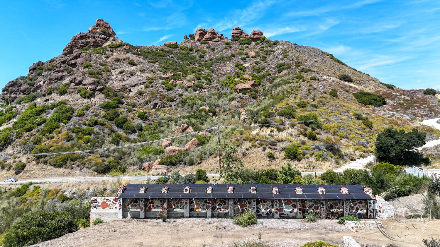 Eagle Feather - exterior, flat roof, natural vegetation, stone walls, solar panel installation, rural location, asphalt access road, desert-like environment, colored stone facade, mountainous setting, landscape of rocky hills, grassy hillside