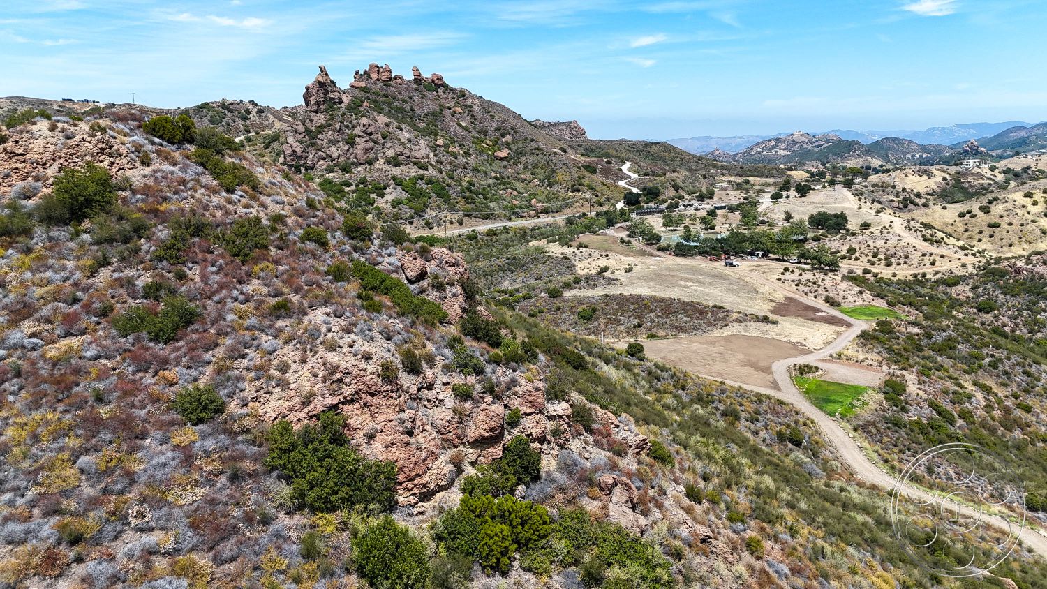 Eagle Feather - rocky terrain, hillside location, rolling hills, dry vegetation, open sky, mountain landscape, scenic overlook, desert environment, natural rock formations, dirt access road, coastal foothills