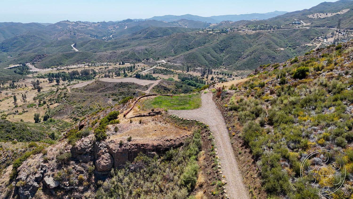 Eagle Feather - exterior, natural landscape, mountain backdrop, gravel driveway, rocky terrain, hillside location, undulating hills, scrubland vegetation, cleared building site, earthy soil