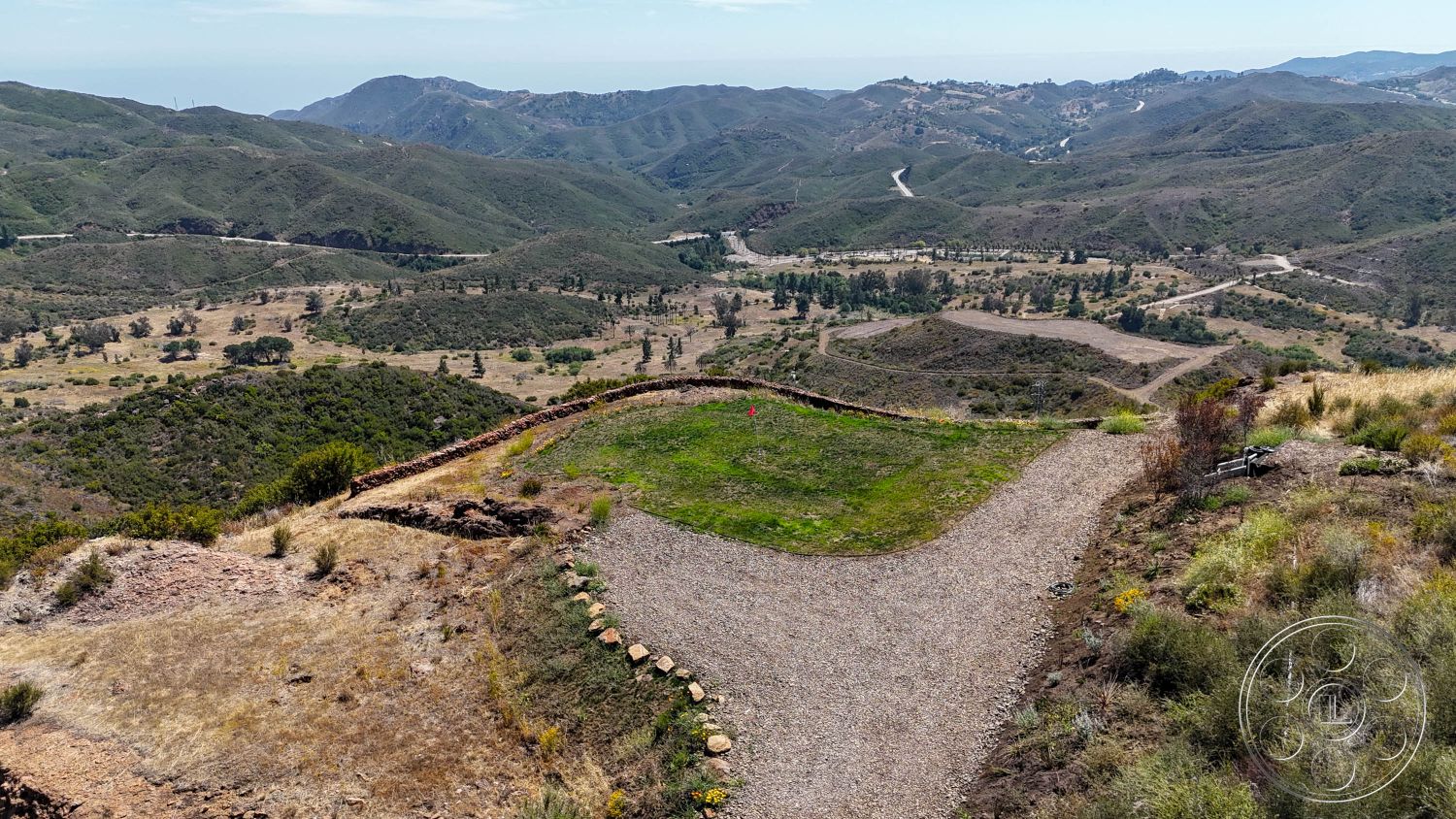 Eagle Feather - exterior, open space, natural landscaping, mountain view, gravel driveway, hillside location, undulating terrain, scenic overlook, green grass area, rocky outcroppings, surrounding foothills, dirt road access, unobstructed skyline