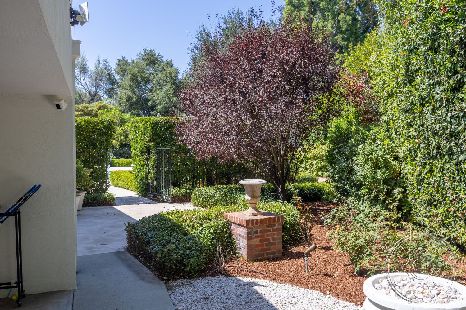 Retro 295 - exterior, flowering shrubs, concrete walkway, lush green hedges, ornamental tree, natural stone border, brick garden urn base, wood mulch garden bed, pathway with hedgerows, detailed garden gate