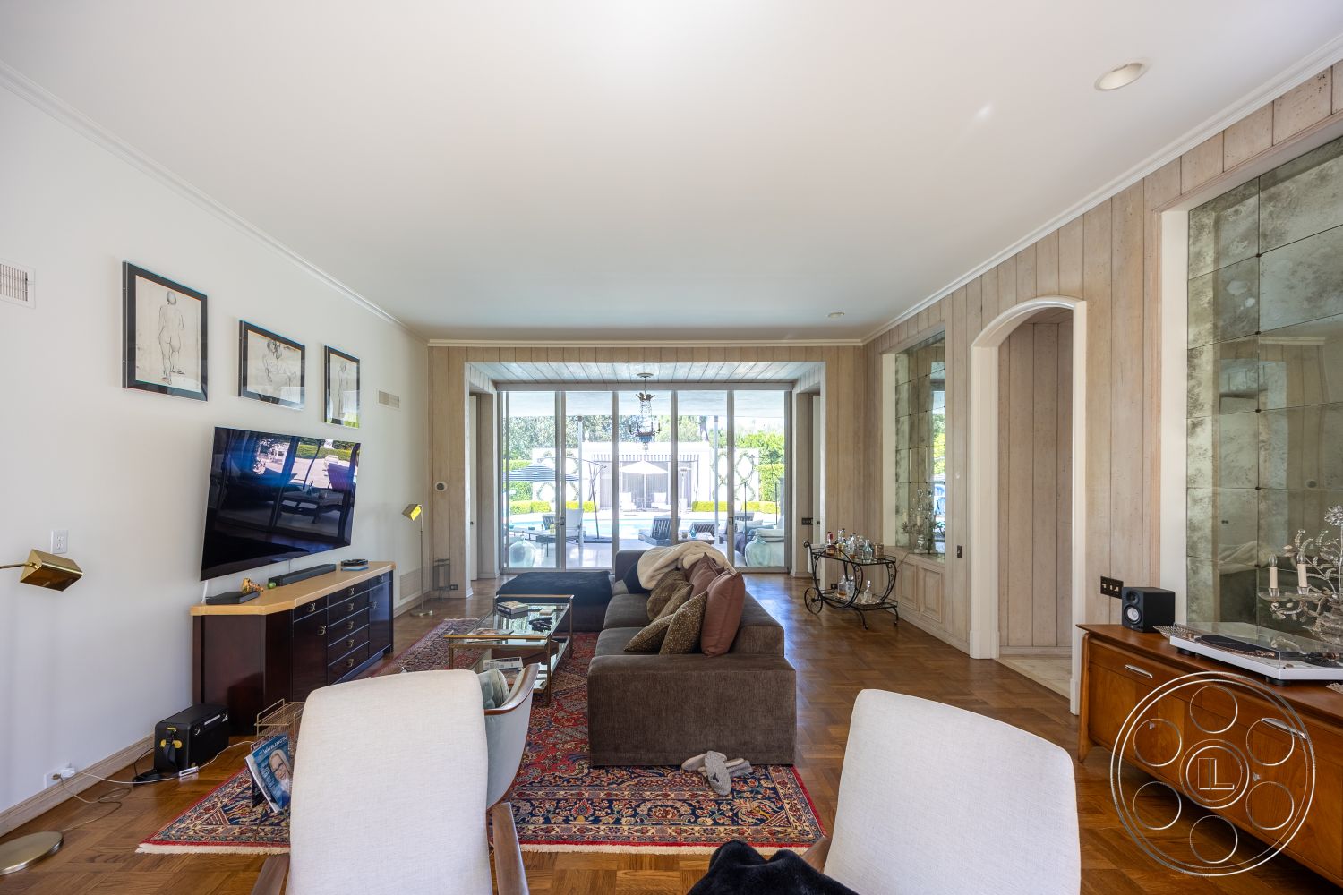 Retro 295 - neutral color palette, contemporary style, hardwood flooring, decorative area rug, large glass sliding doors, cozy seating area, floor-to-ceiling windows, dark wood furniture, crown molding details, open living area, modern television stand, light wood paneling walls, art framed wall decor