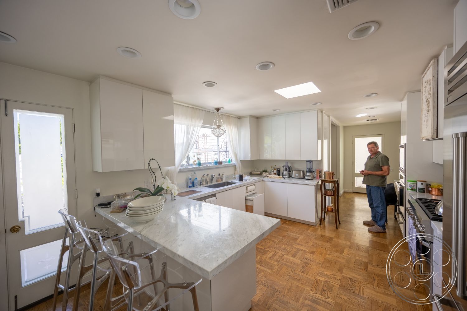 Retro 295 - stainless steel appliances, floor-to-ceiling windows, wood parquet flooring, open kitchen layout, marble kitchen countertop, minimalist kitchen design, single-basin kitchen sink, transom window above door, light-colored wall treatment, shiny kitchen cabinet doors, elegant dining bar, modern kitchen chandelier
