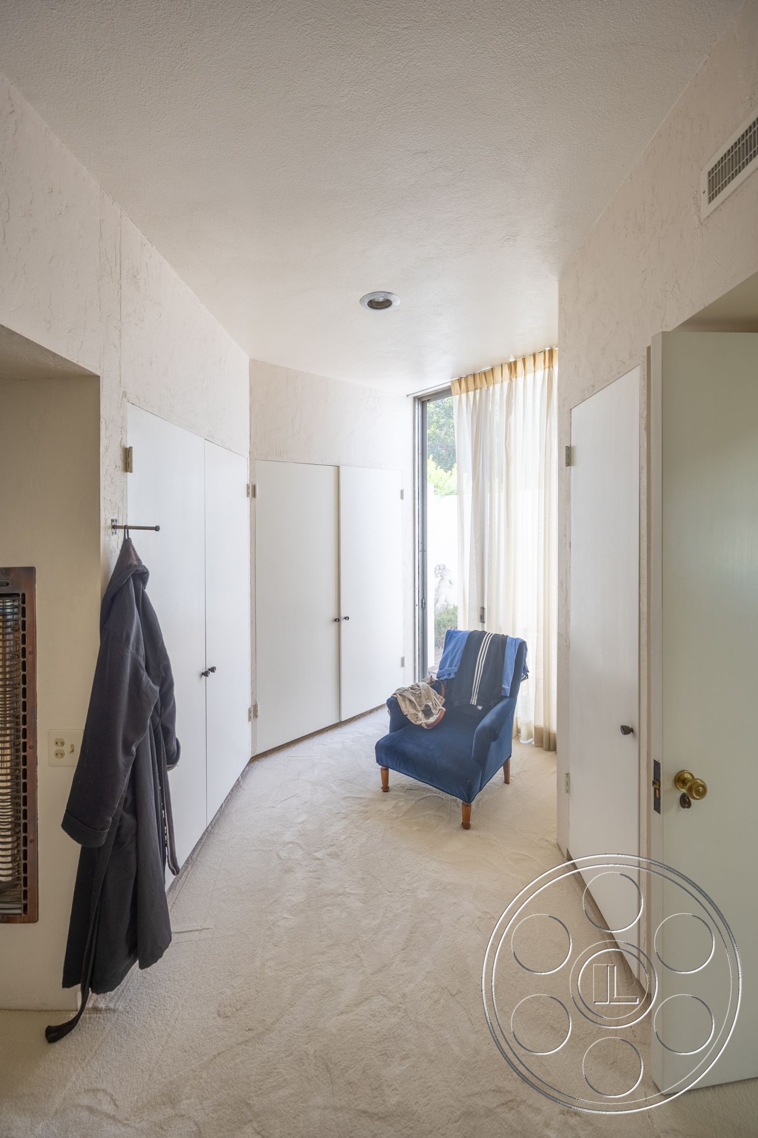 Retro 295 - natural light, soft lighting, floor-to-ceiling windows, textured plaster walls, striped throw blanket, modern minimalist style, carpet bedroom flooring, white sliding closet doors, blue upholstered armchair