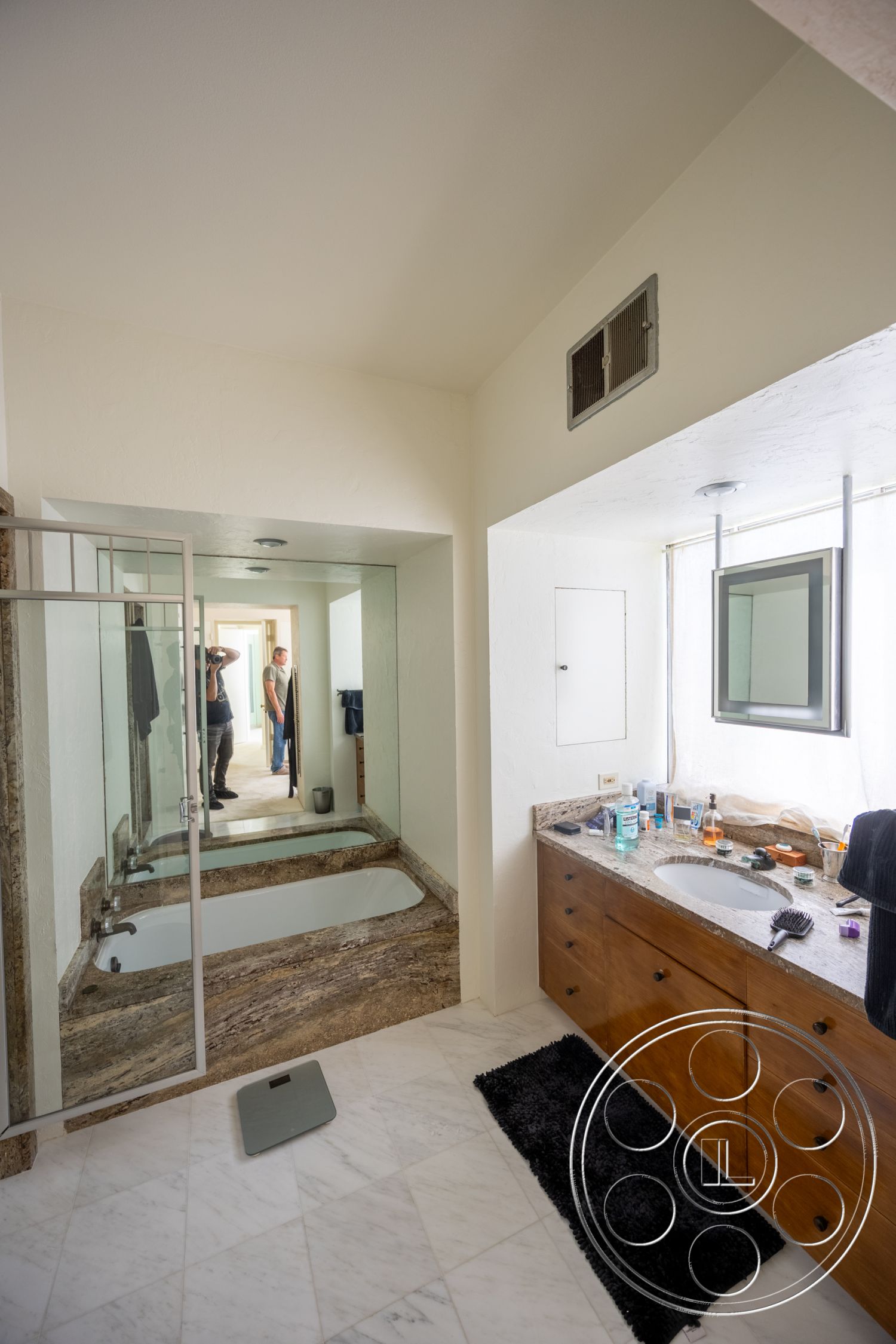 Retro 295 - glass shower enclosure, mirrored wall, dark area rug, white textured plaster walls, marble bathroom flooring, floor-to-ceiling mirrors, wood bathroom vanity, granite bathtub border, ceiling-mounted recessed lighting