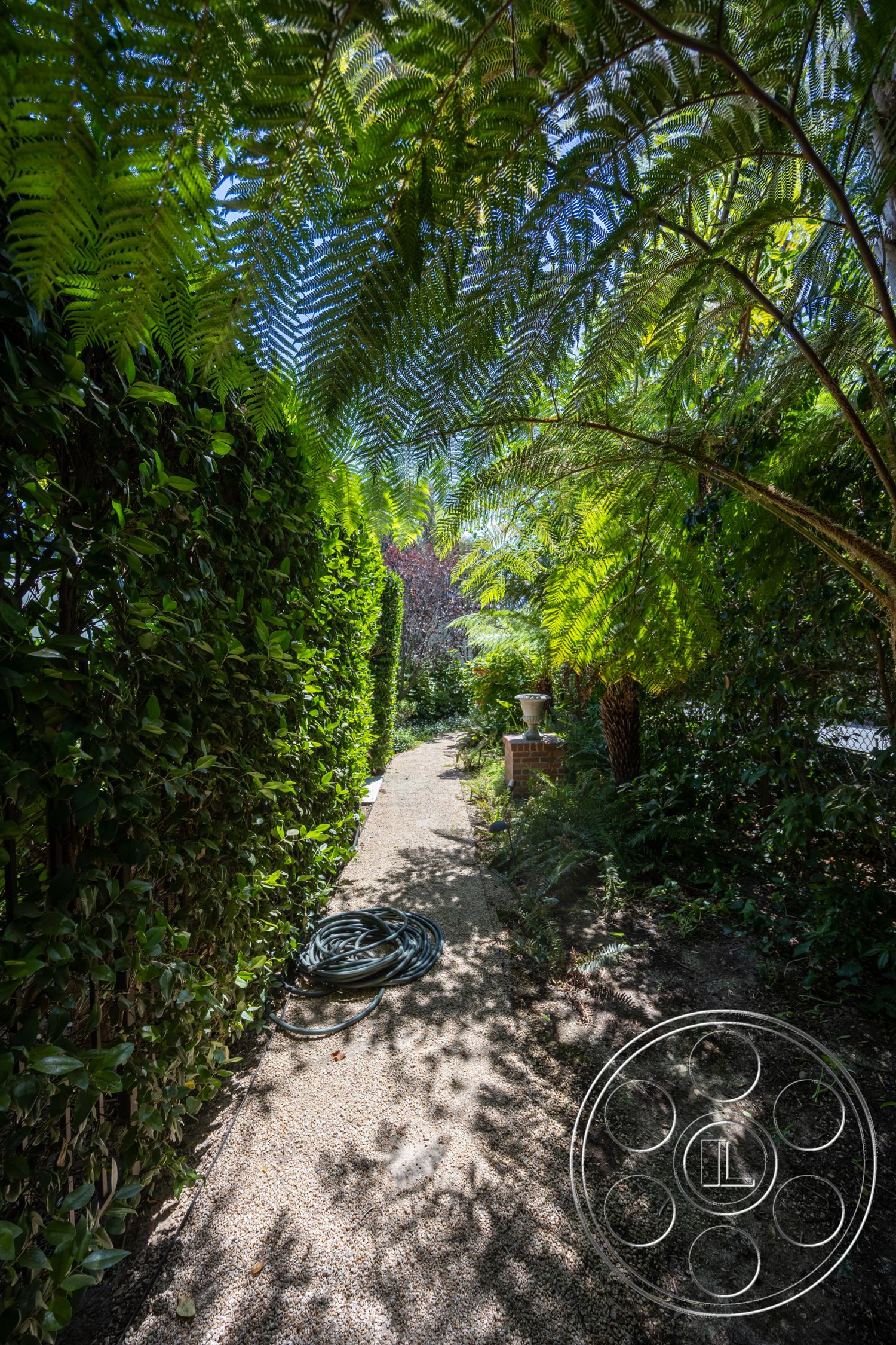 Retro 295 - exterior, gravel pathway, brick planter, tropical garden setting, green hedge borders, fern canopy, garden hose
