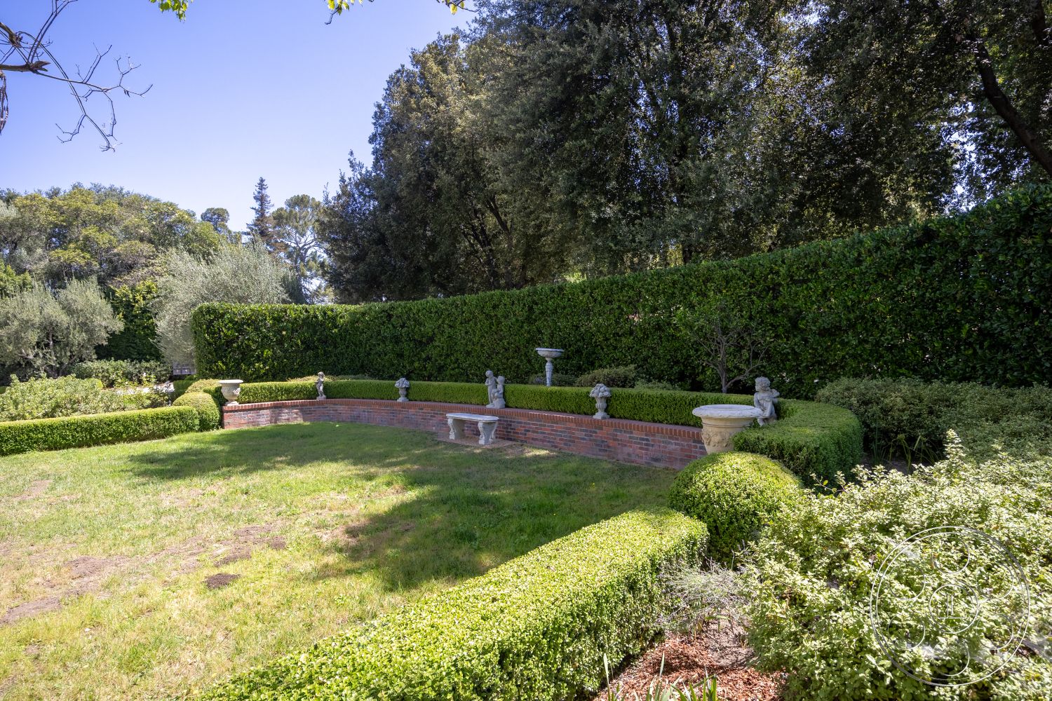 Retro 295 - exterior, landscaped garden, surrounding trees, flowering shrubs, lawn area, manicured landscaping, boxwood hedge, brick garden wall, sculptural stone garden statues, curved garden bed