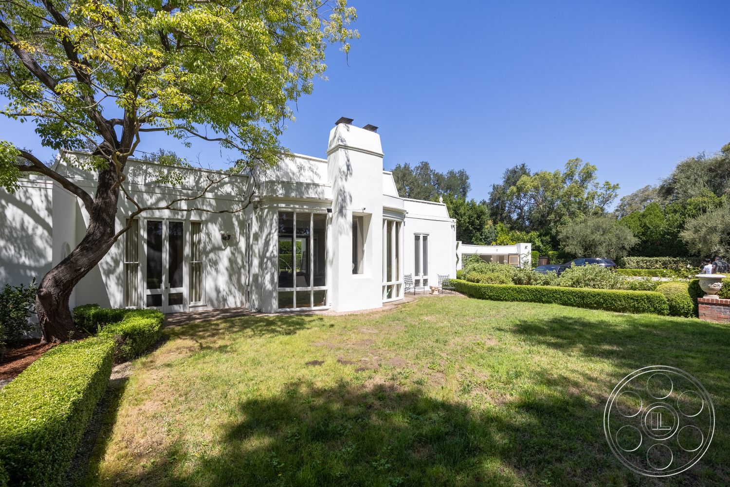 Retro 295 - exterior, landscaped garden, white stucco walls, flat roof, brick walkway, modern architectural style, large floor-to-ceiling windows, manicured hedges, sunny backyard setting, pergola area