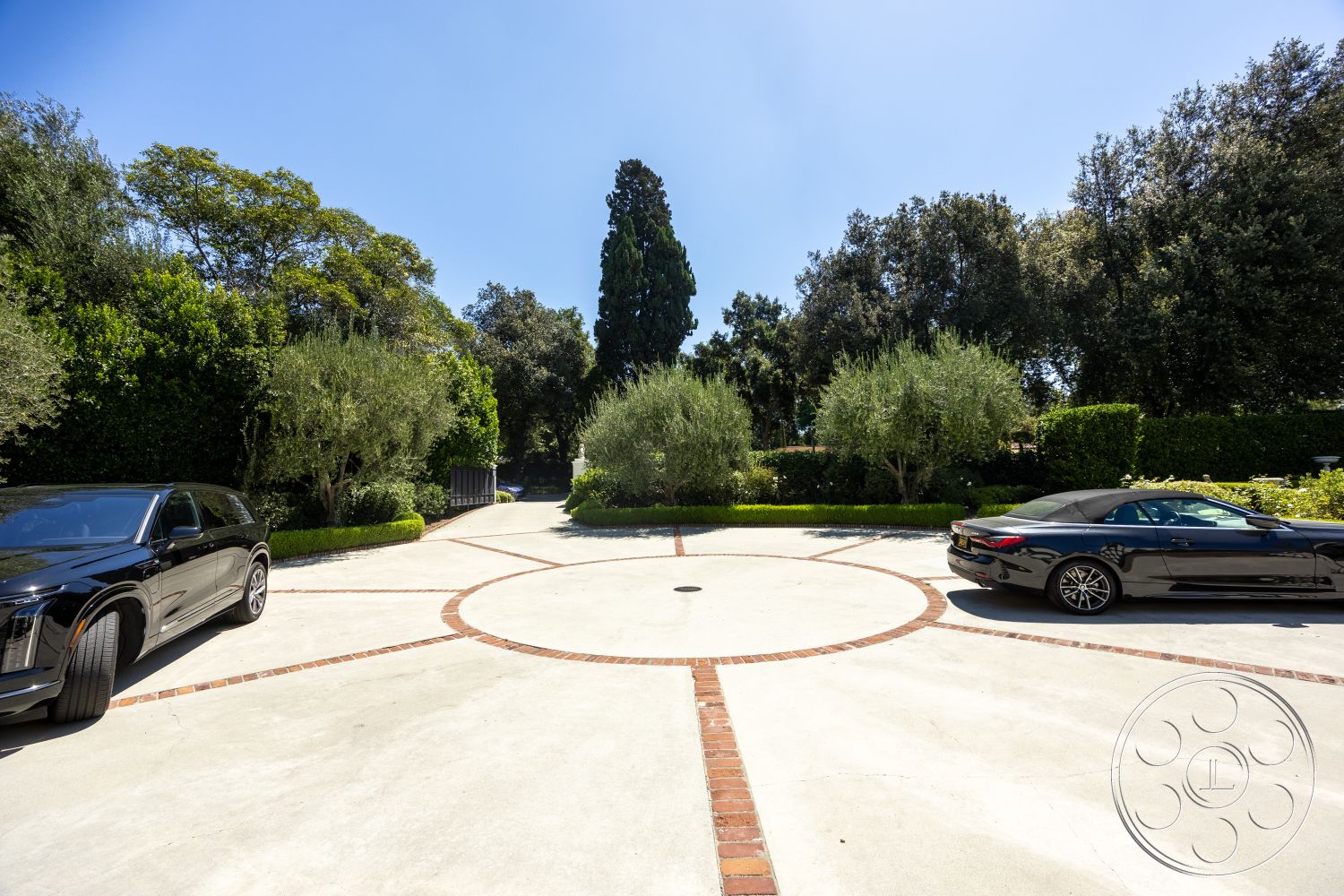 Retro 295 - exterior, circular driveway, lush landscaping, concrete driveway, clear blue sky, ornamental shrubs, brick driveway pavers, trees surrounding the property, two parked luxury cars