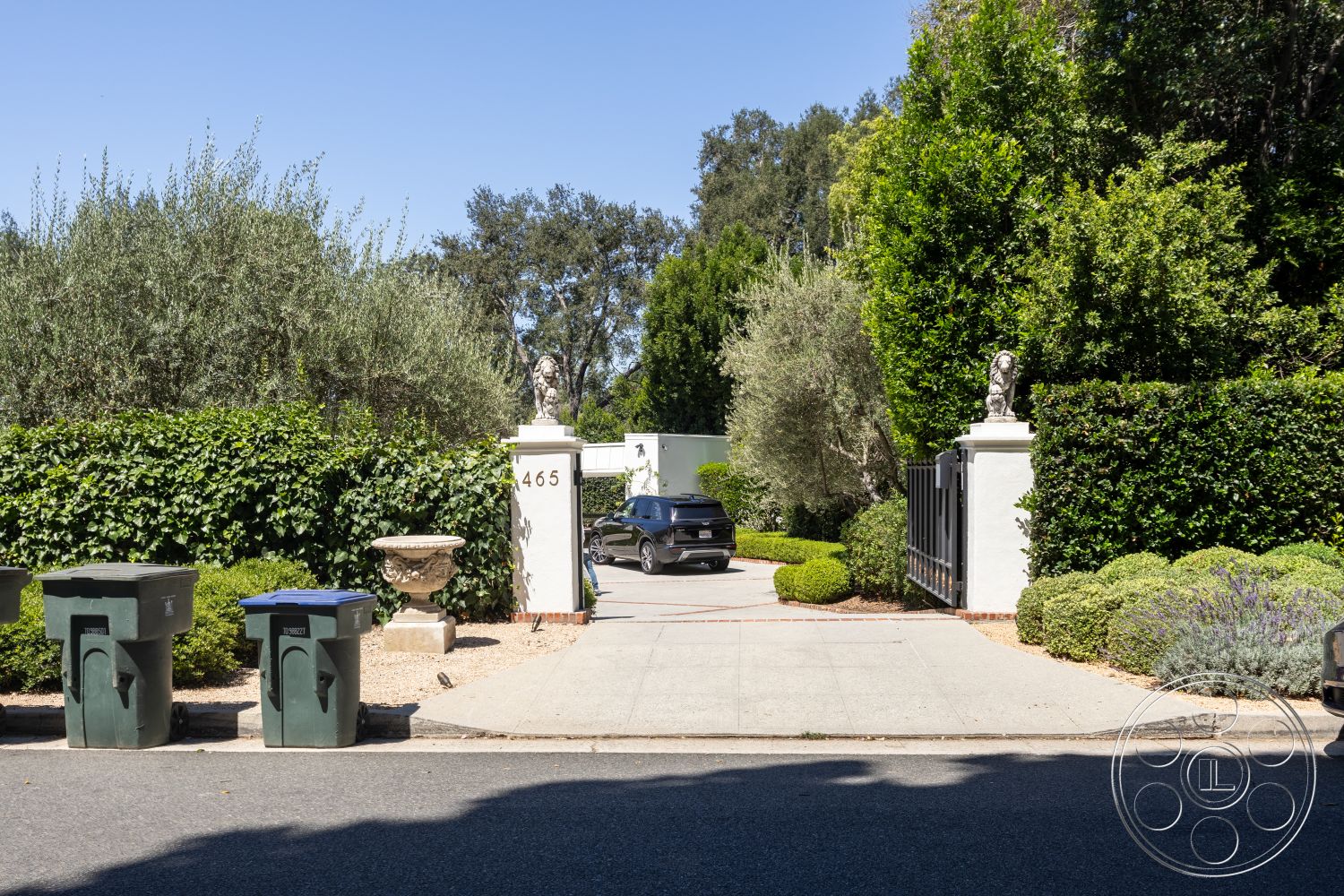 Retro 295 - exterior, paved driveway, green foliage, concrete driveway, lush hedges, stone gate pillars, blue recycling bin, manicured garden landscaping, solid wooden gate, ornamental stone planter, decorative statuary, green waste bins, suburban street view