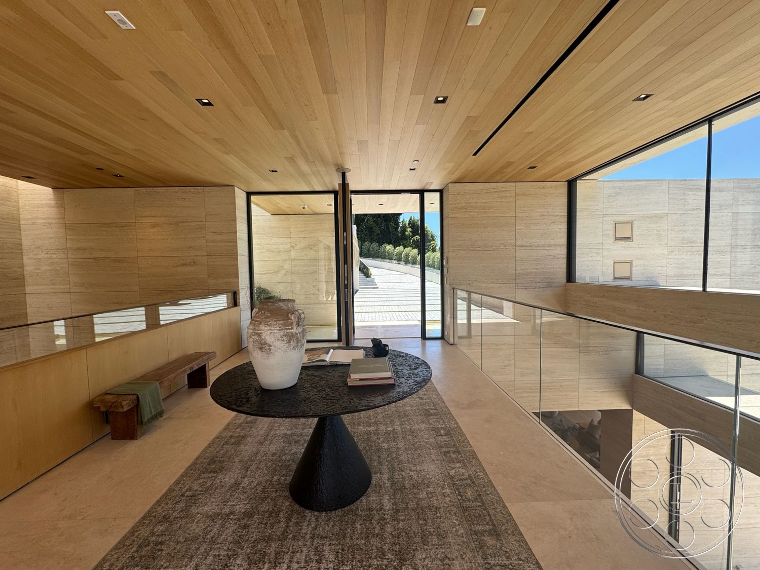 Chalon Estate - textured area rug, minimalist design elements, open concept layout, stone flooring, modern decor accents, glass wall features, black round dining table, natural light flooding in, wood plank ceiling, built-in bench seating, light-colored wood paneling