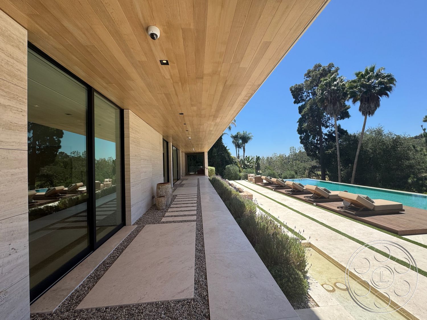 Chalon Estate - exterior, modern architecture, minimalist design, rectangular swimming pool, floor-to-ceiling windows, gravel pathway, concrete pool deck, horizontal wood siding, wood plank ceiling, stone exterior walls, tile patio flooring, framed glass doors, landscaped garden with palm trees