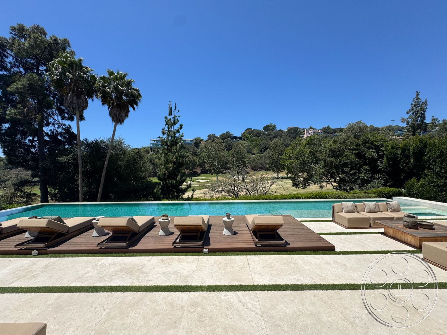 Chalon Estate - exterior, landscaped garden, modern outdoor furniture, hilltop view, clear blue sky, open-air terrace, infinity pool, tropical palm trees, concrete pool deck, wood deck surface, green grass borders, tan lounge chairs, granite stone tiles
