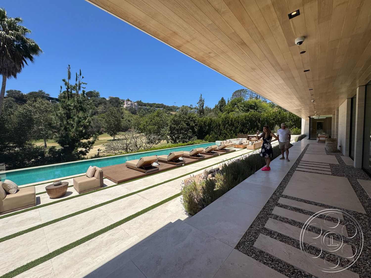 Chalon Estate - exterior, lush greenery, potted plants, wooden ceiling, sliding glass doors, rectangular swimming pool, horizontal wood fencing, concrete walkway, sunny outdoor setting, landscaped garden area, stone patio flooring, wooden pool deck, modern outdoor lounge chairs