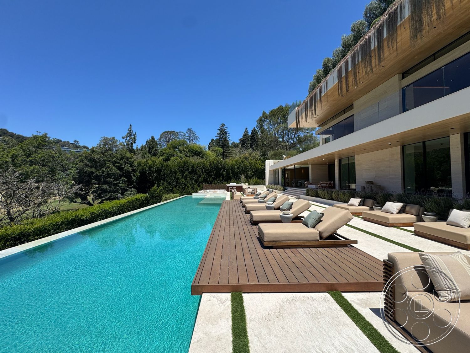 Chalon Estate - exterior, sliding glass doors, glass railing, natural stone flooring, modern architectural style, infinity pool, horizontal wood paneling, outdoor lounge chairs, concrete pool deck, rectangular pool, landscaped garden area, wood deck surface, large outdoor seating area, awning overhang, open view of surrounding greenery