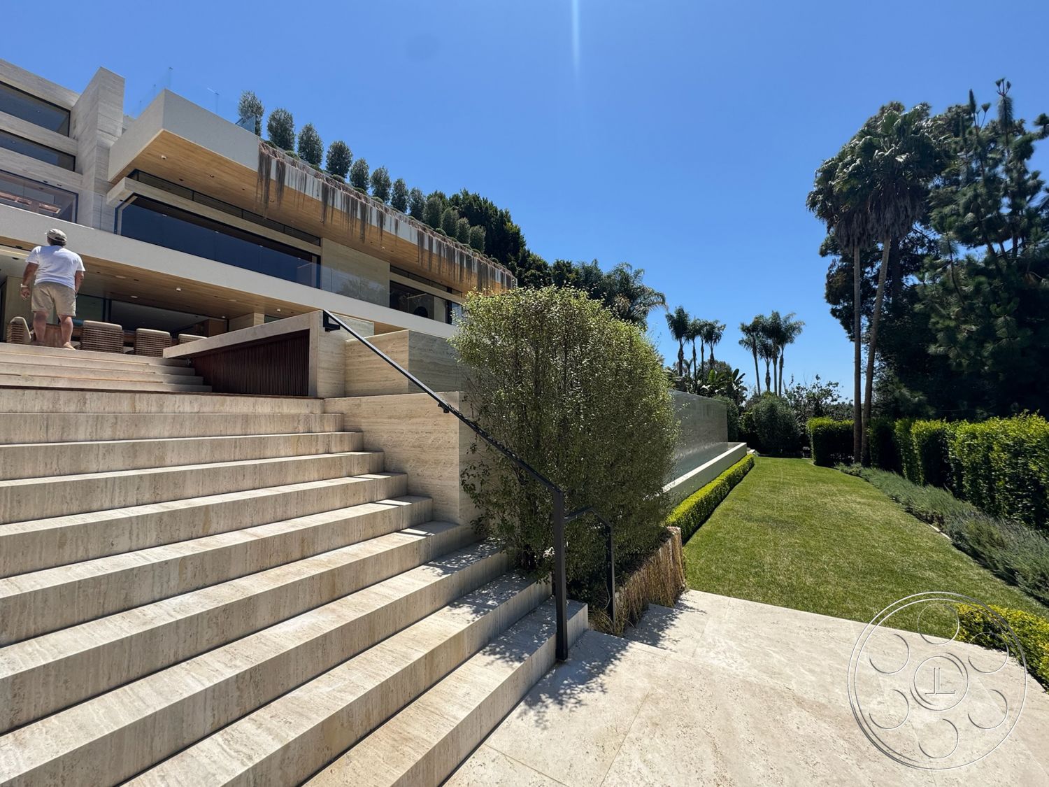 Chalon Estate - exterior, landscaped garden, modern architecture, low-maintenance garden, patio area, concrete wall, paved pathway, manicured hedges, rectangular layout, tropical vegetation, horizontal wood slats, luxury home setting, limestone steps, reinforced glass railings, wood soffit ceiling, architectural water feature, view of blue sky