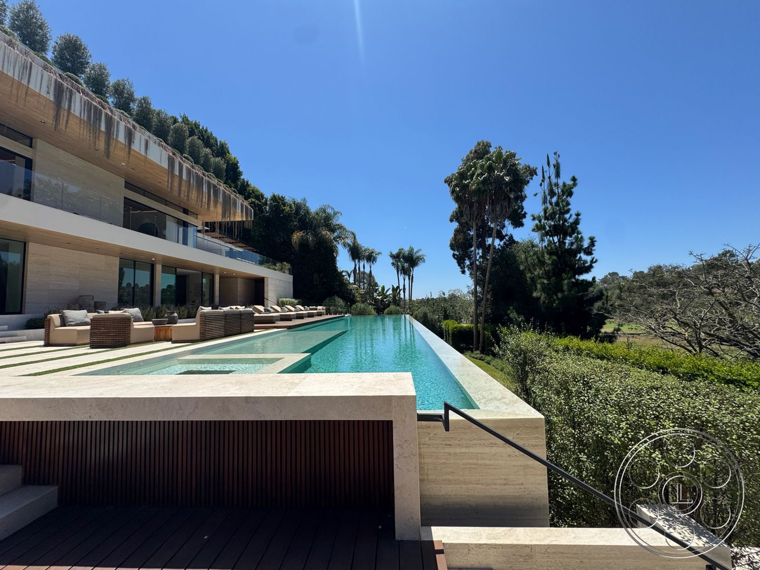 Chalon Estate - exterior, landscaped garden, palm trees, large glass windows, outdoor lounge area, modern architectural style, natural stone walls, lap pool, horizontal wood siding, stone pool deck, wood beam ceiling, concrete patio floor, rectangular infinity pool, built-in outdoor seating, plush outdoor cushions, marble pool border