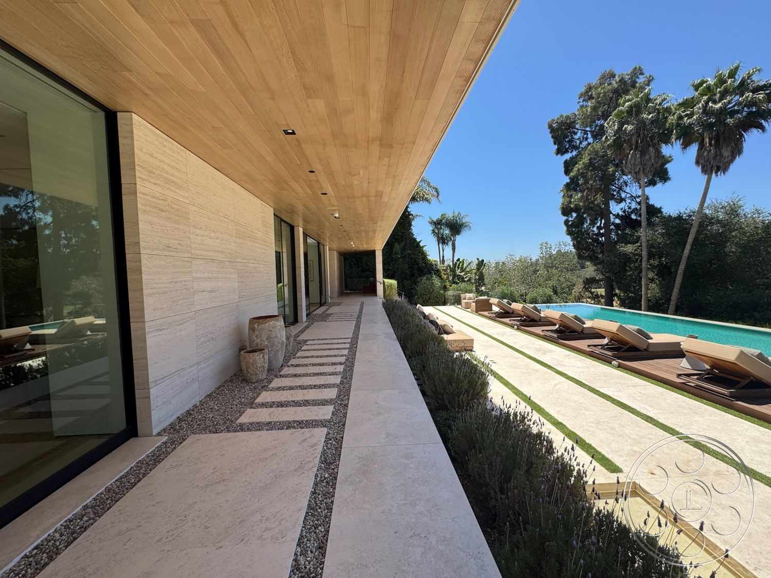 Chalon Estate - exterior, glass sliding doors, rectangular swimming pool, modern architectural style, gravel landscaping, wood plank ceiling, limestone facade walls, stone paving walkway, wood sun loungers, lavender garden beds