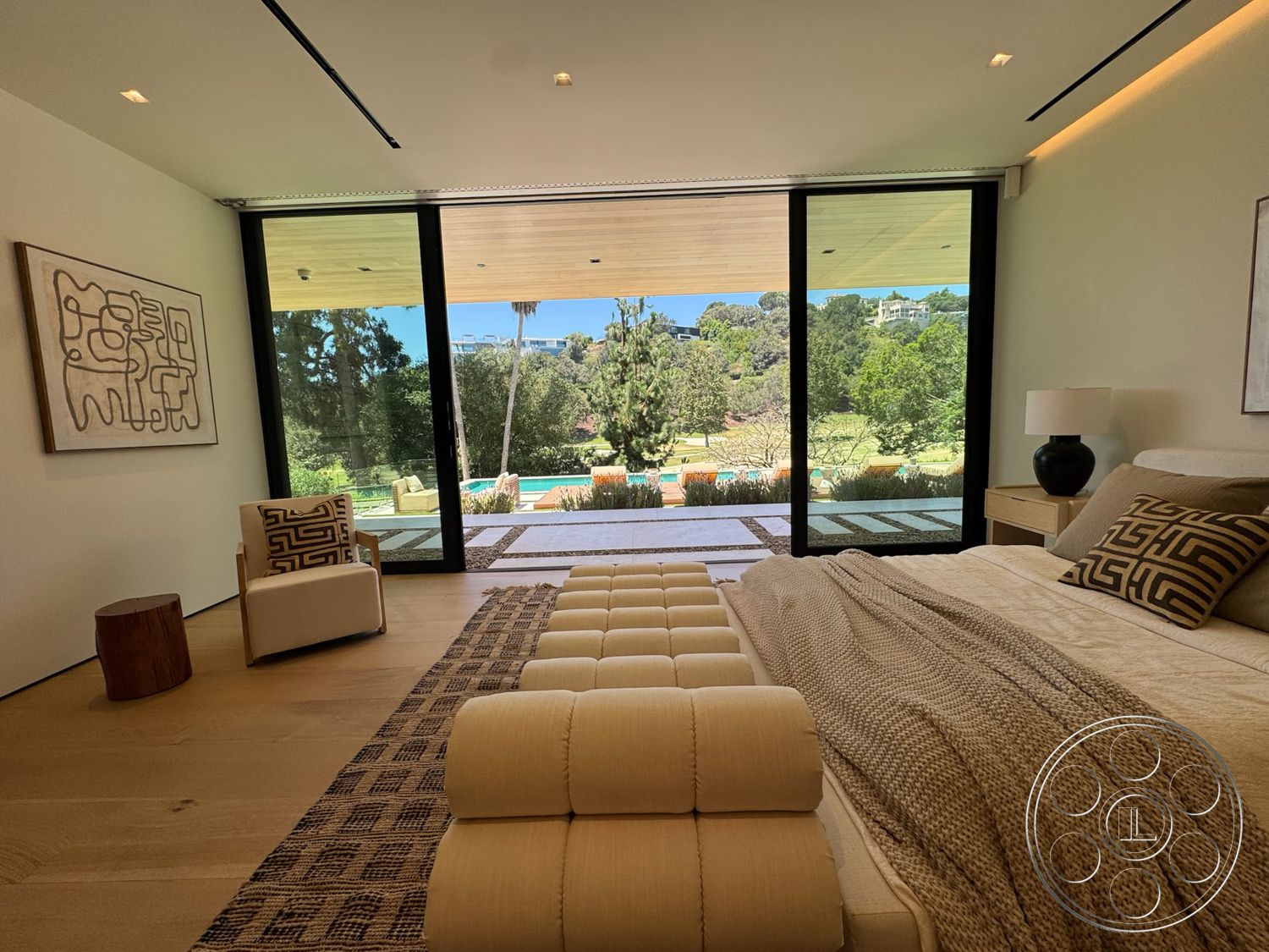 Chalon Estate - natural light, contemporary design, textured area rug, abstract wall art, sliding glass doors, large floor-to-ceiling windows, decorative throw pillows, modern side table, potted plants outside, hardwood bedroom floors, wood beam ceiling, white painted walls, view of landscaped garden, seating area with upholstered chair