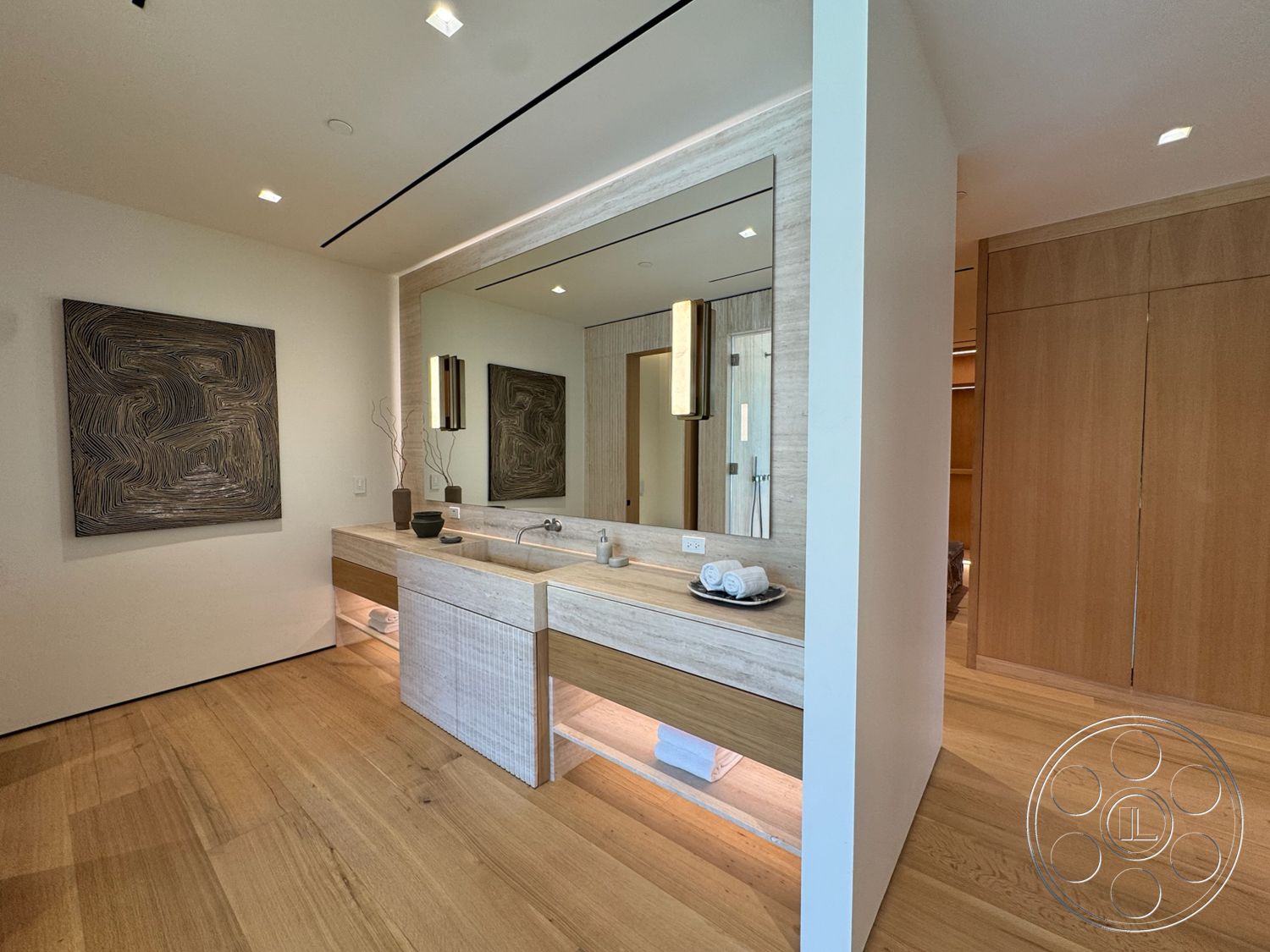 Chalon Estate - neutral color palette, wood flooring, open layout, floating vanity, minimalist design elements, built-in cabinetry, light oak hardwood floors, ample natural light, exposed concrete sink base, backlit bathroom mirror, soft white wall treatments, artwork wall feature, modern linear light fixtures, single sink bathroom, shower access
