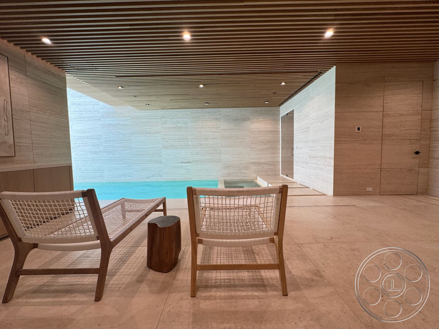 Chalon Estate - minimalist design, large glass windows, modern lounge chairs, wood slat ceiling, natural wood side table, rectangular indoor pool, limestone walls, travertine flooring, built-in pool spa feature
