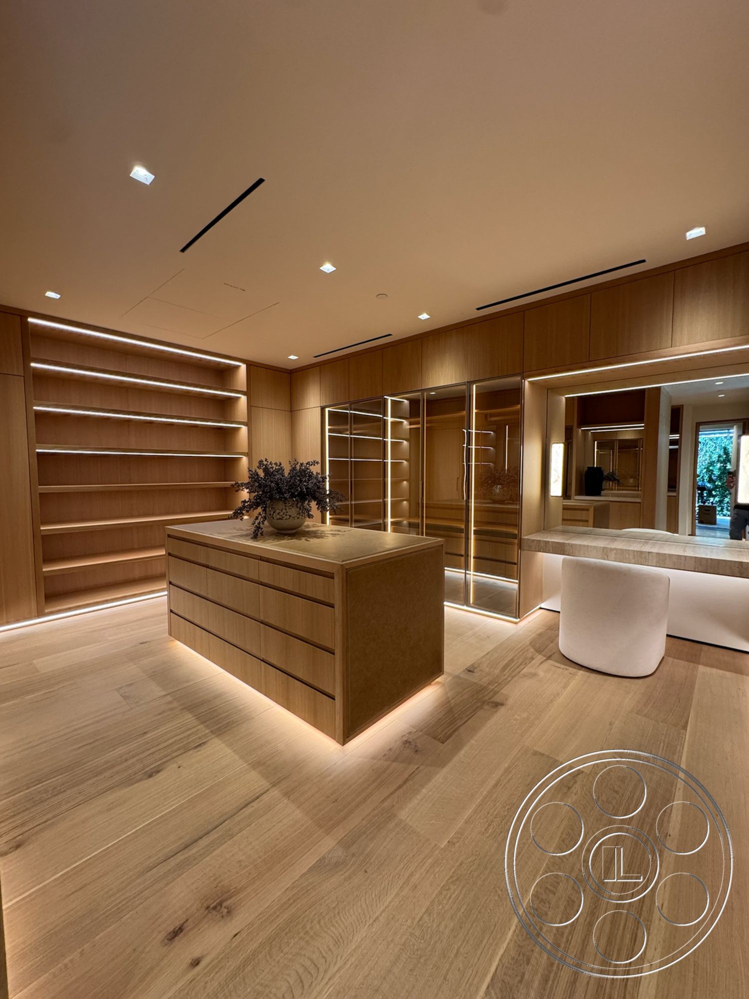 Chalon Estate - neutral color palette, contemporary style, minimalist design, light wood cabinetry, soft lighting features, decorative plant arrangement, oak wood floors, modular storage shelves, backlit linear shelving, built-in mirror wall, spacious dressing area, wide drawer storage