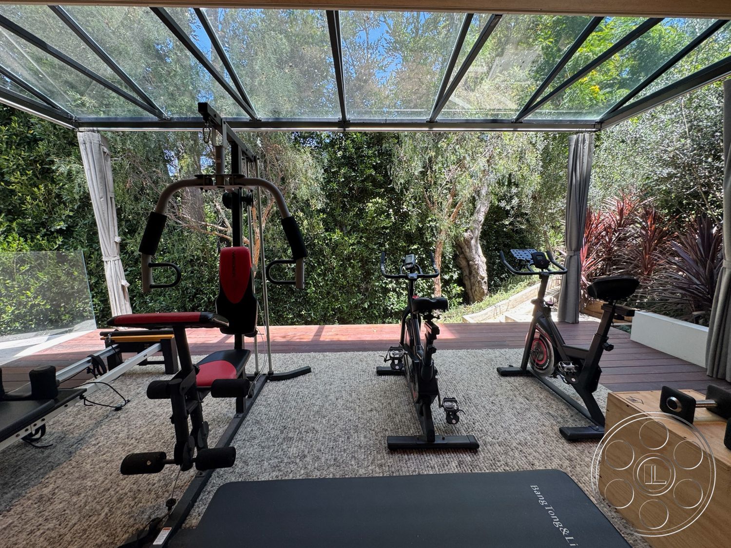 Chalon Estate - exercise bikes, textured carpet flooring, wood deck flooring, natural greenery backdrop, interior fitness room, soft fabric curtains, glass roof structure, operator's weight machine, sliding glass partition