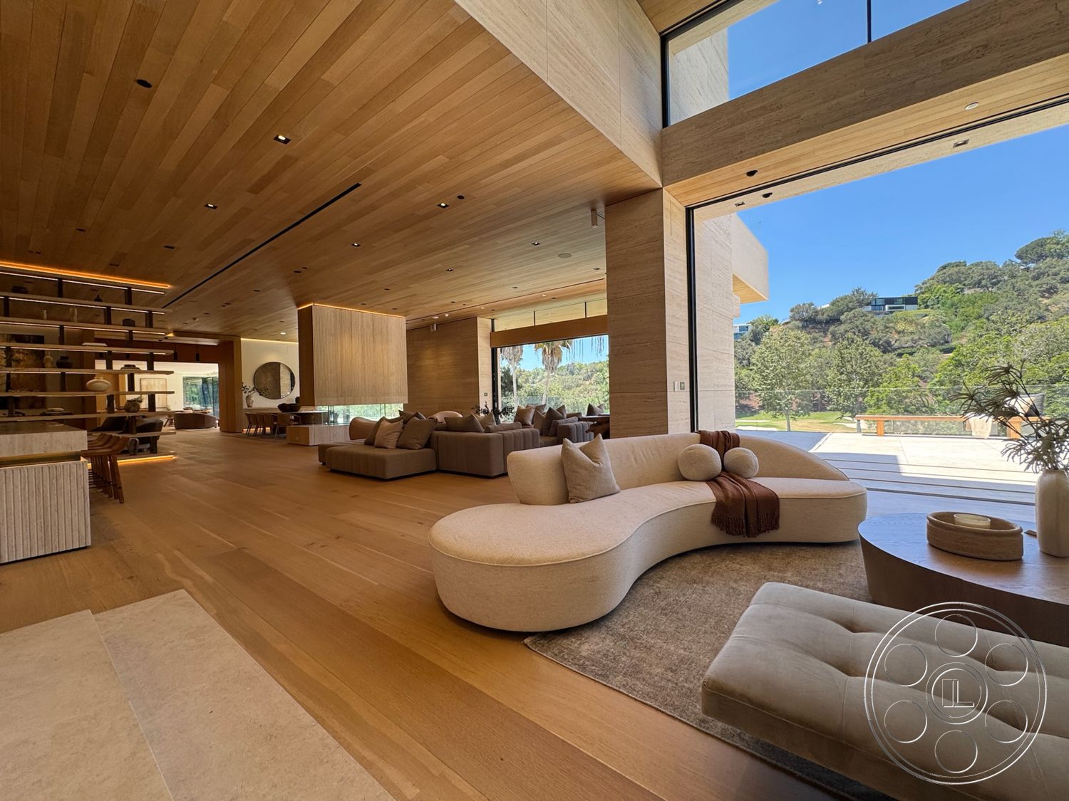 Chalon Estate - high ceilings, large glass sliding doors, open floor plan, textured accent wall, natural wood flooring, floor-to-ceiling windows, contemporary architecture, outdoor view, minimalist coffee table, sustainable design elements, curved sectional sofa, built-in shelving unit, neutral-toned area rug, light wood ceiling planks, horizontal wood panel wall