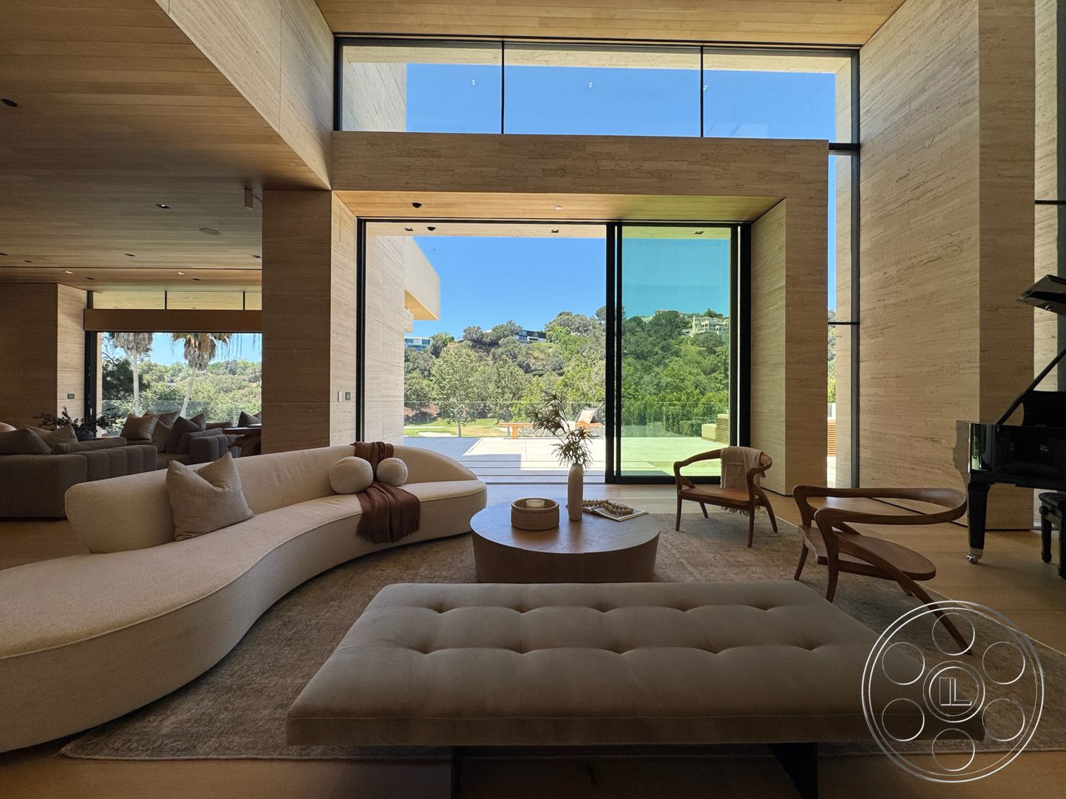 Chalon Estate - minimalist design, textured area rug, open floor plan, indoor-outdoor flow, landscape view, floor-to-ceiling windows, smooth concrete flooring, circular coffee table, bright and airy atmosphere, wood dining chairs, wood paneling walls, natural stone feature wall, rounded sectional sofa, modern piano