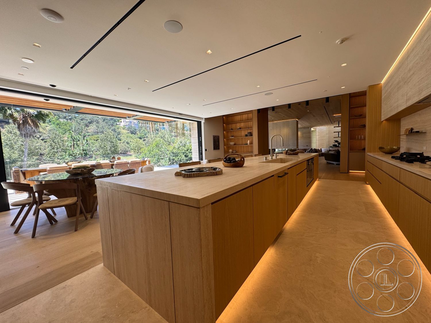 Chalon Estate - minimalist decor, natural light, contemporary design, large glass sliding doors, wood cabinetry, wood dining table, built-in shelving, stone countertop, marble flooring, seamless indoor-outdoor flow, architectural lighting, kitchen appliances, modern dining area, open-concept kitchen, linear ceiling lights, expansive kitchen island, textured wood walls, pantry cabinets
