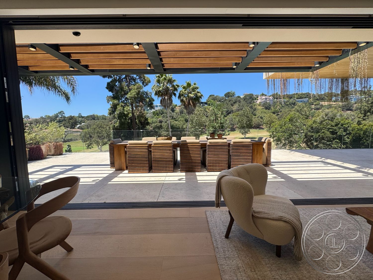 Chalon Estate - natural light, modern design, area rug, open concept layout, glass sliding doors, glass railing, exposed wooden beams, outdoor dining area, wooden pergola, concrete patio flooring, rustic wooden dining table, view of trees and landscape, soft upholstered armchair