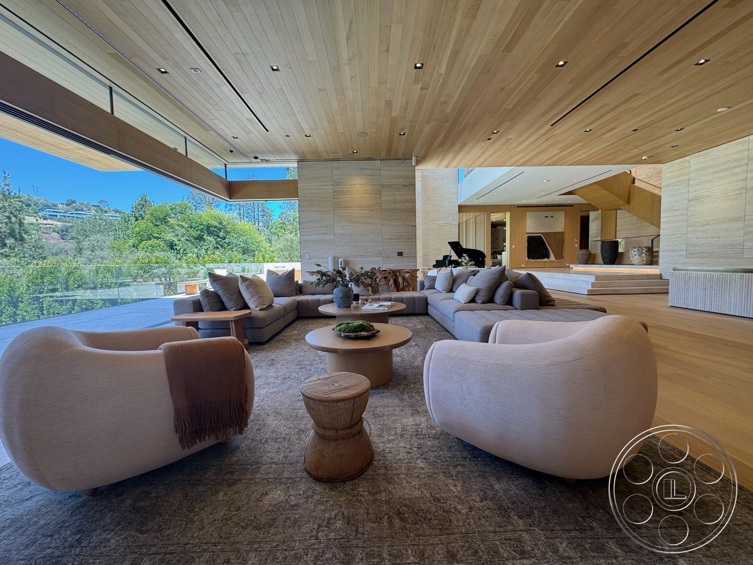 Chalon Estate - stone accent wall, light hardwood flooring, open floor plan, glass sliding doors, floor-to-ceiling windows, textured plaster walls, round wooden coffee table, modern minimalist design, natural light-filled space, wood beam ceiling, modern sectional sofa, curved upholstered chairs, light wooden ceiling panels