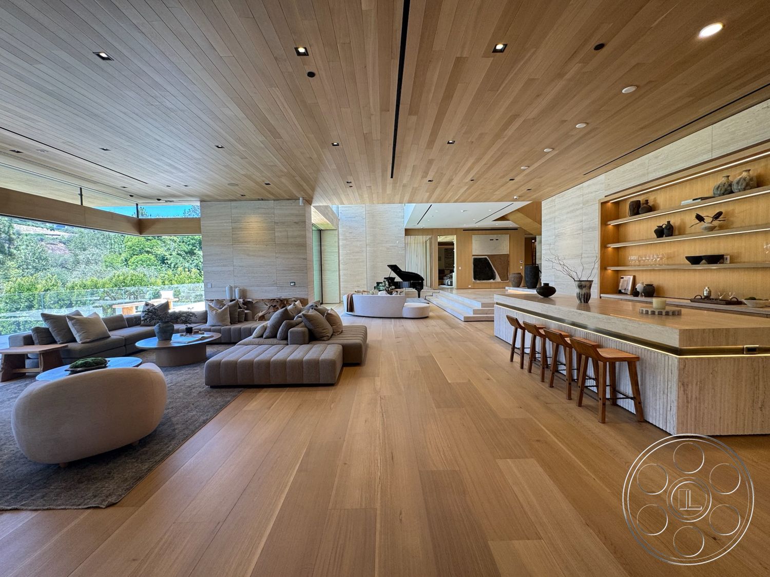 Chalon Estate - neutral color palette, natural light, spacious layout, stone accent wall, round coffee table, textured area rug, light hardwood flooring, wood panel ceiling, minimalist furniture, open-concept living space, large floor-to-ceiling windows, modern lounge area, lush greenery view, contemporary art decor, custom built-in shelving, rectangle dining table, soft beige sectional sofa, wood barstools