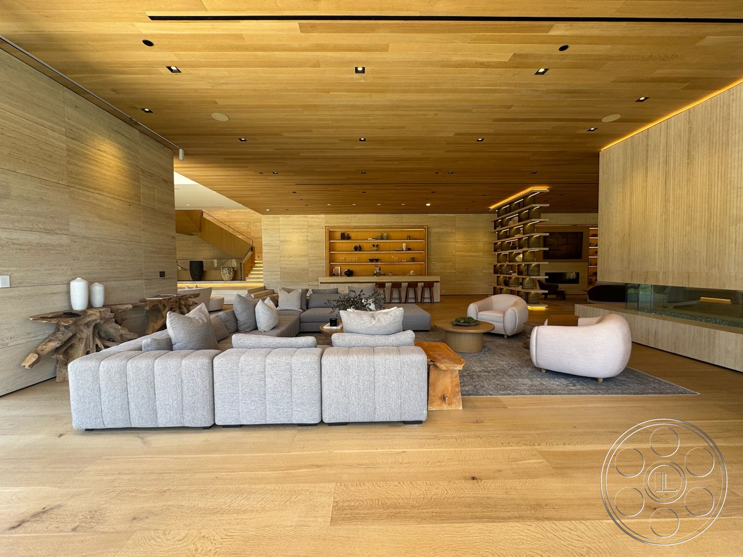 Chalon Estate - contemporary style, hardwood flooring, open floor plan, soft area rug, natural wood coffee table, floor-to-ceiling glass panels, built-in wooden shelving, textured wood accent wall, minimalist home decor, wood ceiling planks, modular fabric sofa, curved upholstered armchairs